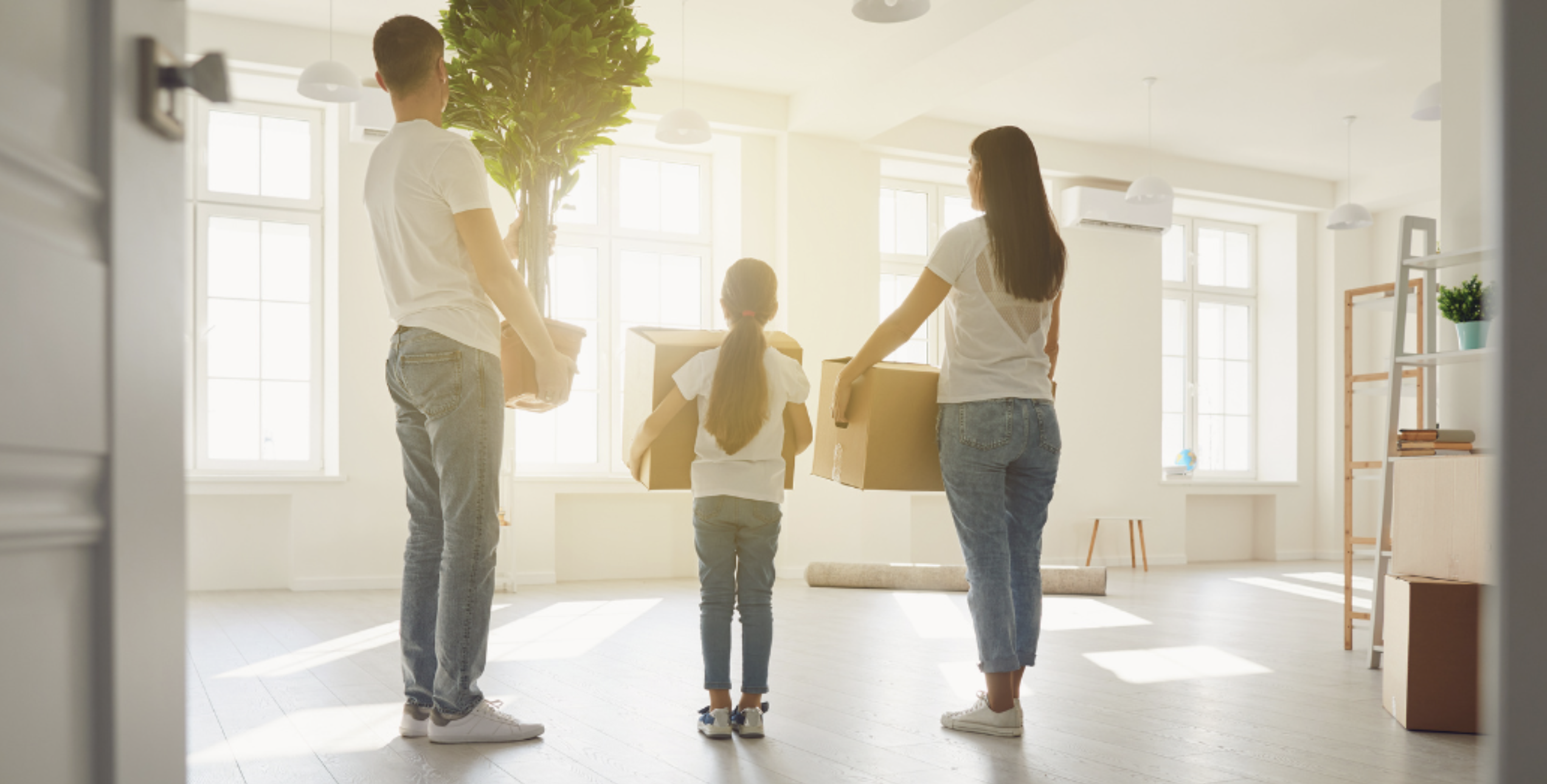 A family carrying boxes and furniture into their new home.